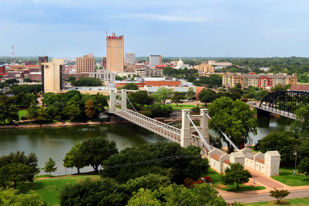 Waco Downtown Suspension Bridge located on the Brazos River with the Alico Building to show community and culture
